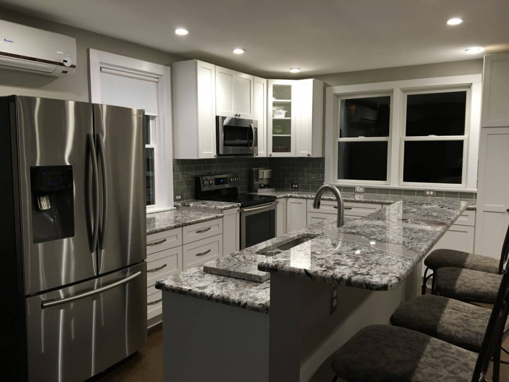 Modern kitchen with polished granite countertops in black, paired with white cabinetry and stainless steel appliances.
